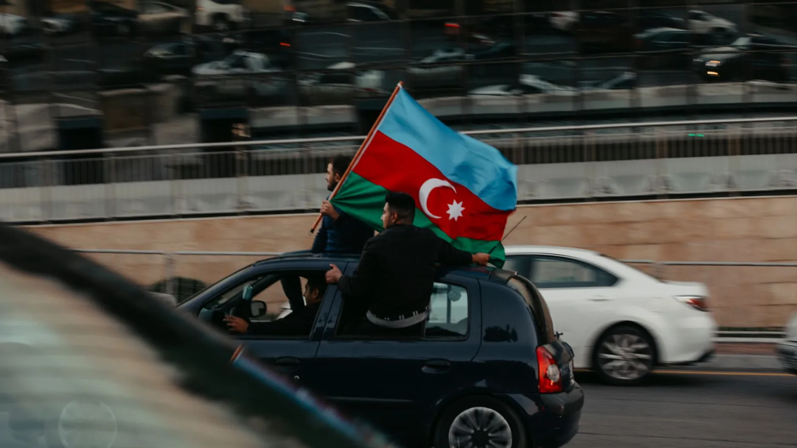 People waving Azerbaijani flag on a city street in Baku, Azerbaijan.