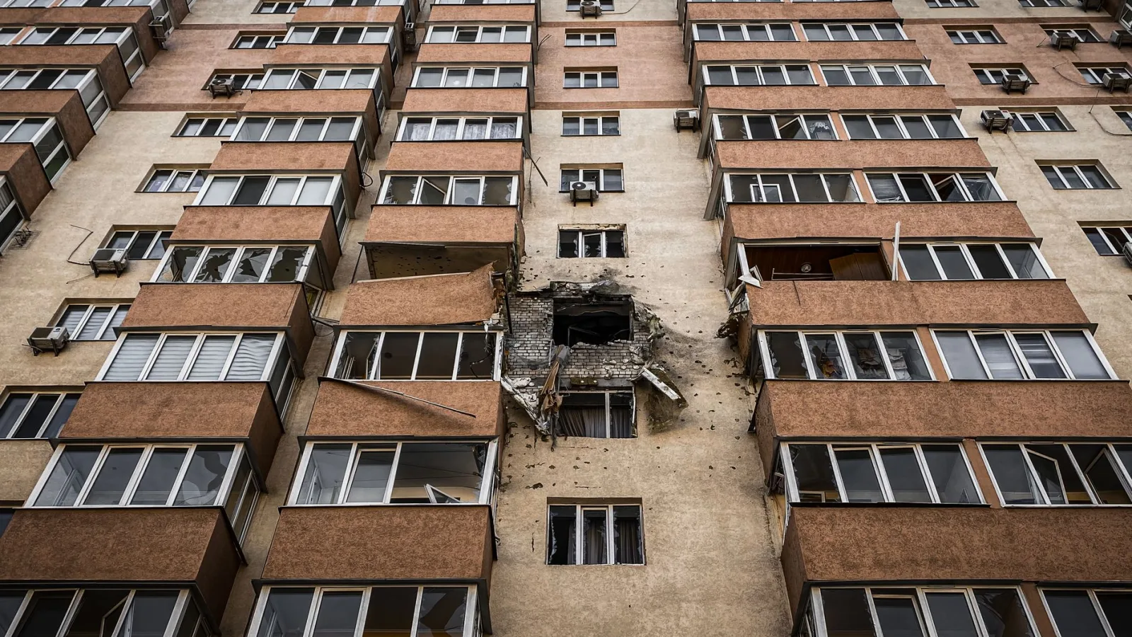 Low-angle view of a damaged apartment building in Kyiv, Ukraine with visible destruction.