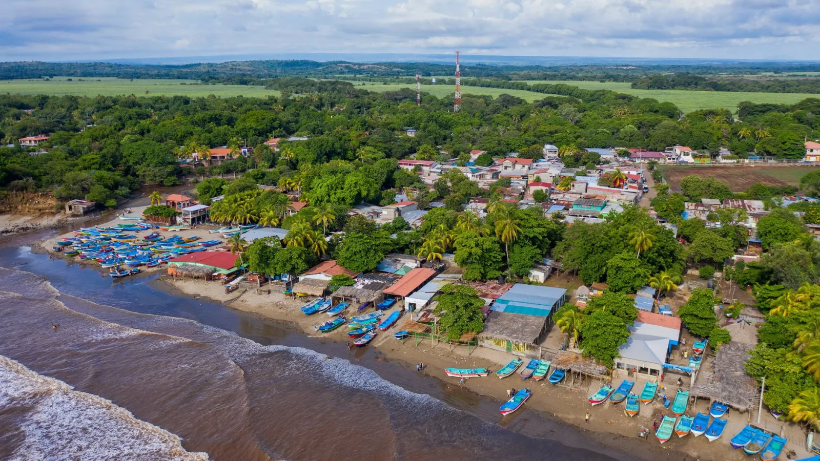 Scenic aerial view of a vibrant coastal town in Nicaragua with colorful boats and lush greenery.