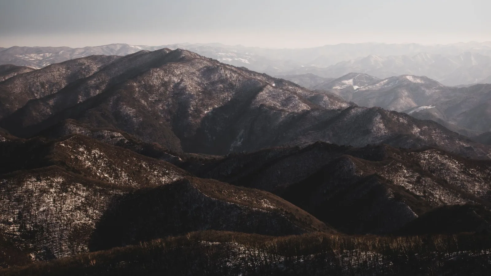 Breathtaking aerial view of Pyeongchang's snow-capped mountains under a clear sky.