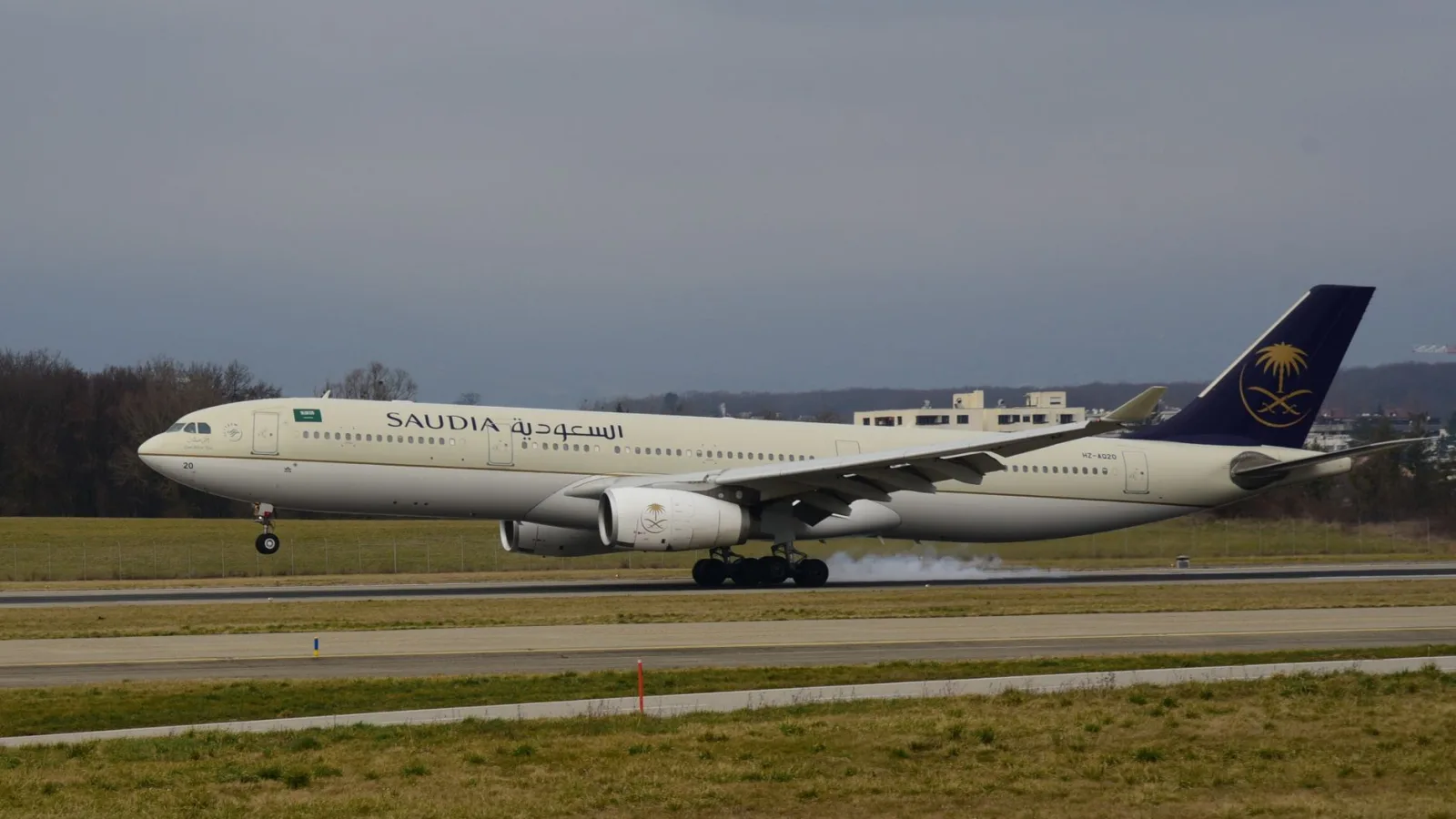 Saudia Airlines aircraft safely lands on a cloudy day in Geneva, showcasing aviation precision.