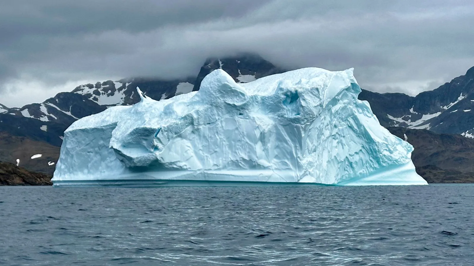 Expansive iceberg floating serenely in the cool waters of Greenland.