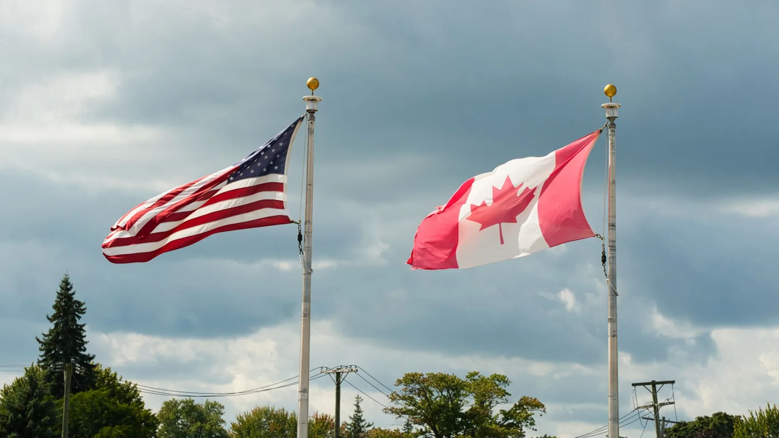 Canadian and American flags waving under a cloudy sky in Harbor Beach, MI.